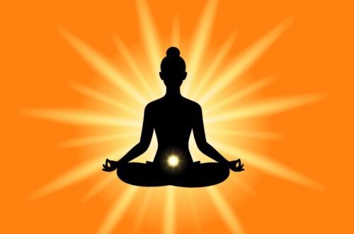 Silhouette of a person meditating in lotus position with a glowing yellow light at the navel, radiating energy on a bright orange background.