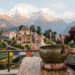 Woman playing a Tibetan singing bowl with a mallet on a terrace overlooking mountains and a monastery in Sikkim.